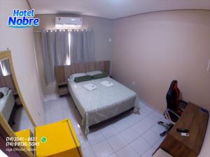 a bedroom with a bed and a table and a chair at Hotel Nobre in Senhor do Bonfim