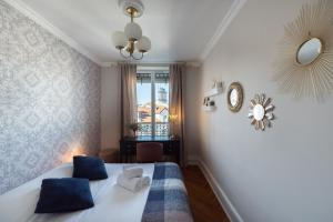 een slaapkamer met een bed met blauwe kussens en een spiegel bij Le Dandy - Grand T3 au pied du métro Garibaldi in Lyon