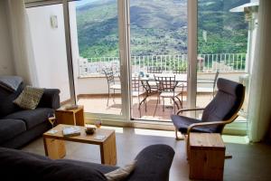 Una sala de estar con un sofá y sillas y una ventana grande. en Guejar Sierra House with Spectacular Views, en Güéjar-Sierra