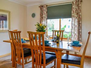 uma sala de jantar com uma mesa de madeira e cadeiras em Bramble Cottage em Dalry