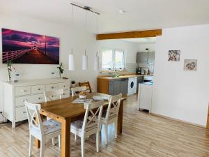 a kitchen and dining room with a wooden table and chairs at Deichgraf - Hedwig meine Perle in Hedwigenkoog