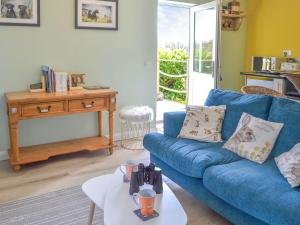 - un salon avec un canapé bleu et une table dans l'établissement Marsh Bungalow, à Halvergate