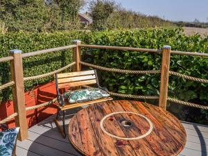 une table en bois et une chaise sur une terrasse dans l'établissement Marsh Bungalow, à Halvergate