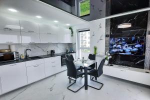a kitchen with white cabinets and a table and chairs at Apartament 10 Glamour Aquapark Reda in Reda