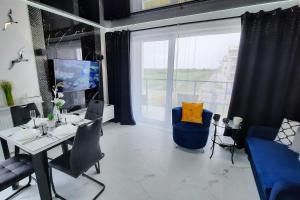 ein Esszimmer mit einem Tisch und Stühlen sowie einem großen Fenster in der Unterkunft Apartament 10 Glamour Aquapark Reda in Reda