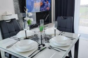 a dining room table with white plates and wine glasses at Apartament 10 Glamour Aquapark Reda in Reda