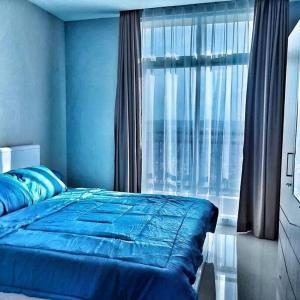a bedroom with a blue bed and a large window at SLEPTOPIA at formosa lvl27 budget unit city and sea view in nagoya jodoh in Jodoh