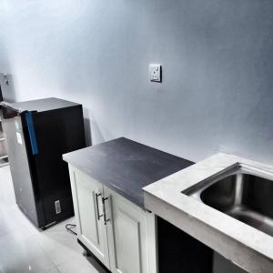 a kitchen with a sink and a black refrigerator at SLEPTOPIA at formosa lvl27 budget unit city and sea view in nagoya jodoh in Jodoh