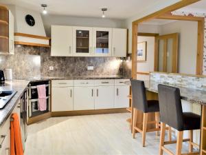 a kitchen with white cabinets and a table and chairs at Cuiltean in Gairlochy
