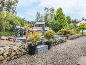een tuin met een bank en een stenen muur bij Cuiltean in Gairlochy