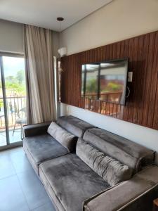 a living room with a couch and a tv on a wall at Flat Île de Pipa Resort - Centro in Pipa