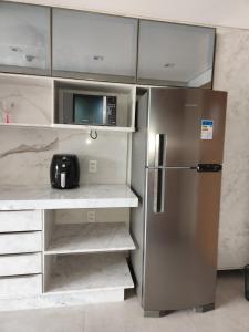 uma cozinha com um frigorífico de aço inoxidável e um micro-ondas em Flat Île de Pipa Resort - Centro em Pipa