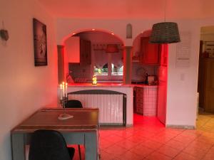 een keuken met rode verlichting en een tafel met stoelen bij La pomme d’amour in Saint-Genest-Lerpt