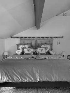 Una foto en blanco y negro de una cama con almohadas en La pomme d’amour en Saint-Genest-Lerpt