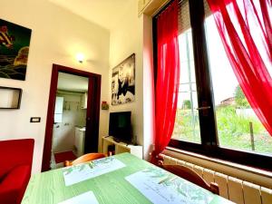 Cette chambre dispose d'une table et d'une fenêtre avec des rideaux rouges. dans l'établissement Kibilù - Via Colonna con parcheggio vicinanze Ospedale di Circolo, à Varèse