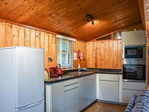 a kitchen with white appliances and wooden walls at Pine Lodge in Ellington