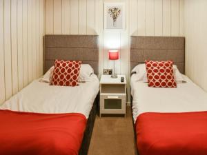 two beds with red pillows in a room at Pine Lodge in Ellington