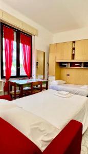 een slaapkamer met 2 bedden en een tafel met rode gordijnen bij Kibilù - Via Colonna con parcheggio vicinanze Ospedale di Circolo in Varese