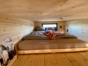 1 cama en una habitación pequeña en una cabaña de madera en WiNZiG Wohnen Tiny House SKADI am Weserstrand, en Elsfleth
