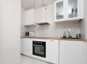 - une cuisine blanche avec des placards blancs et un four noir dans l'établissement Renovated apartment metro, parking included, near Porte Versaille, à Vanves