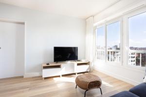 ein weißes Wohnzimmer mit einem TV und einem Stuhl in der Unterkunft Renovated apartment metro, parking included, near Porte Versaille in Vanves