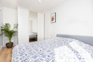 Schlafzimmer mit einem Bett mit einer blauen und weißen Bettdecke in der Unterkunft Renovated apartment metro, parking included, near Porte Versaille in Vanves