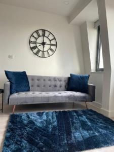 a living room with a couch and a clock on the wall at Premier Suite- Bedford city centre with free gym & parking in Bedford