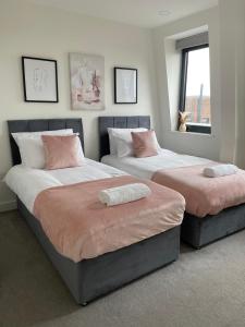 ein Schlafzimmer mit 2 Betten und rosa Kissen darauf in der Unterkunft Premier Suite- Bedford city centre with free gym & parking in Bedford
