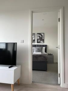 a bedroom with a bed and a tv and a mirror at Premier Suite- Bedford city centre with free gym & parking in Bedford