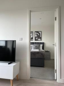 ein Schlafzimmer mit einem Bett, einem Fernseher und einem Spiegel in der Unterkunft Premier Suite- Bedford city centre with free gym & parking in Bedford