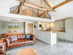 a living room with a leather couch and a kitchen at The Old Stables - Uk38576 in Aston Cantlow