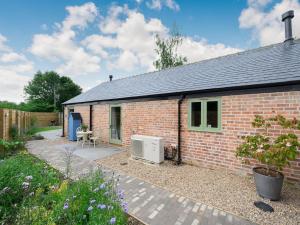 a red brick house with a patio in front of it at The Old Stables - Uk38576 in Aston Cantlow
