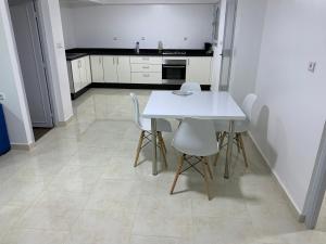 una cucina con tavolo bianco e sedie bianche di Appart de proximité à bayo a Berkane