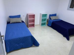 two beds in a room with blue comforter at Appart de proximité à bayo in Berkawe