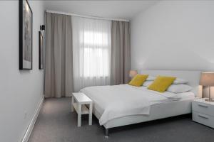 ein weißes Schlafzimmer mit einem großen weißen Bett und gelben Kissen in der Unterkunft Zagreb City Apartments in Zagreb