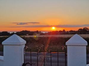 a sunset behind a white fence with a gate at The.deerparkcottage in Lurgan