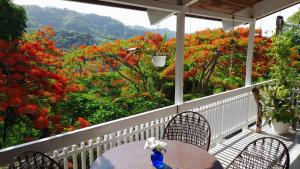 a table and chairs on a porch with red flowers at Neita's Nest in Kingston