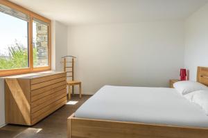 ein Schlafzimmer mit einem Bett, einer Kommode und einem Fenster in der Unterkunft Nachtigall EG in Bettmeralp