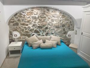 ein Schlafzimmer mit einem blauen Bett und einer Steinmauer in der Unterkunft La mia casetta country chic in Ozieri