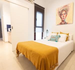 - une chambre blanche avec un grand lit et une couverture jaune dans l'établissement GoToSeville ALTAIR SUITES, à Séville