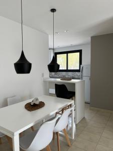 a white kitchen with a white table and chairs at Cbmona Suites in Villa Mercedes