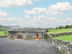 a stone cottage in a field with a stone wall at Scaley Beck - Uk39151 in Threlkeld