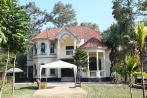 a house with a white umbrella in front of it at Aminvilla resort - family stay to explore Sylhet in Sylhet