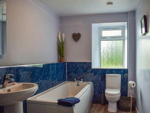 a bathroom with a tub and a sink and a toilet at Southview Cottage in Cupar