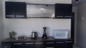 a kitchen with black cabinets and a counter with a microwave at ACONCHEGO DE CANELA/RS in Canela