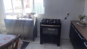 a kitchen with a stove top oven next to a sink at ACONCHEGO DE CANELA/RS in Canela