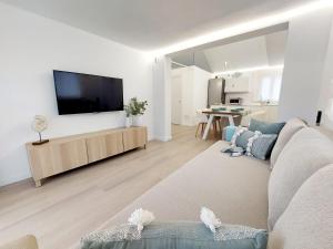 a living room with a couch and a flat screen tv at Bungalow de diseño hidromasajes terraza y piscina. in San Bartolomé de Tirajana