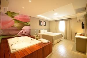 Habitación de hotel con bañera y cama en Business Park Hotel, en Hortolândia