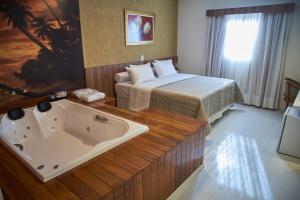 a hotel room with a bed and a bath tub at Business Park Hotel in Hortolândia