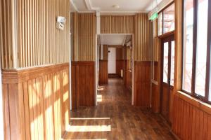 un couloir vide avec des murs et des fenêtres lambrissés dans l'établissement Hostal Ochen, à Punta Arenas